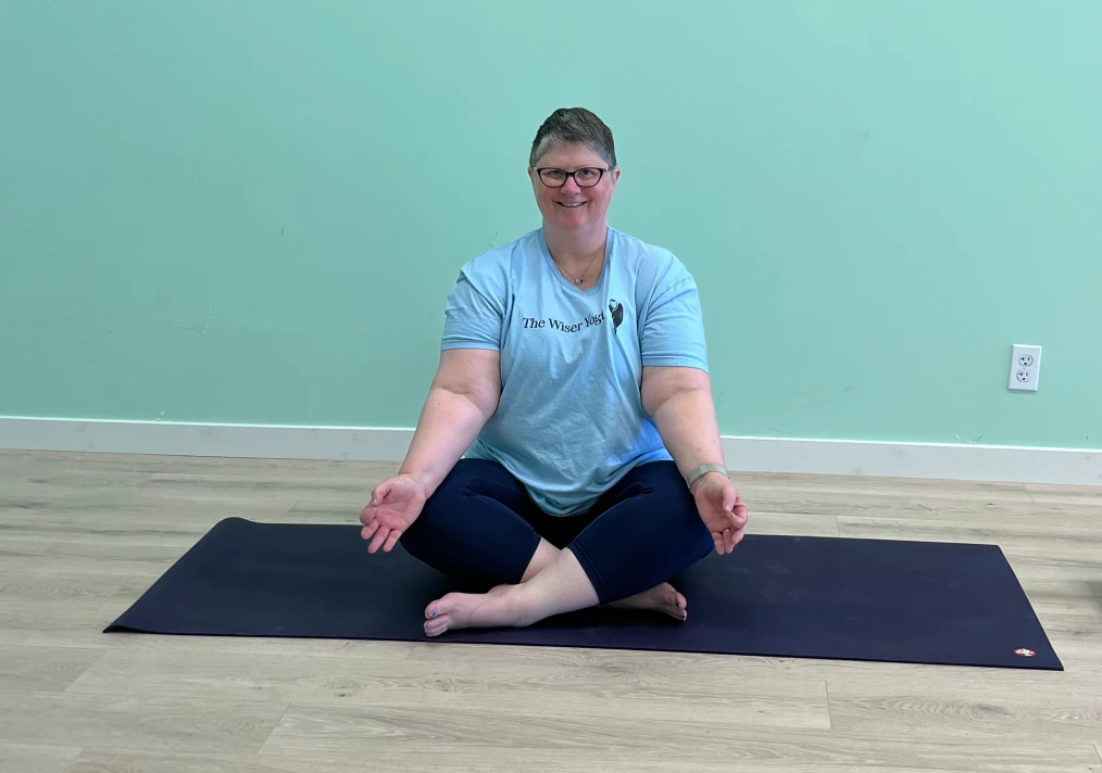 A woman sitting on the ground in a yoga pose.