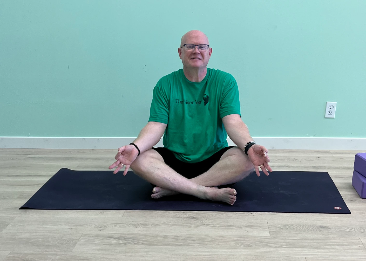 A man sitting on the ground in a yoga pose.